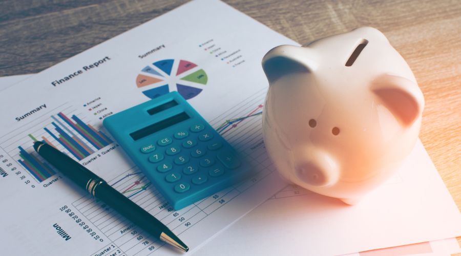 pen, calculator, and piggy bank on top of finance reports
