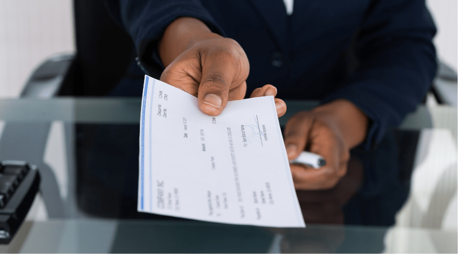 Woman holding out a paycheck in one hand