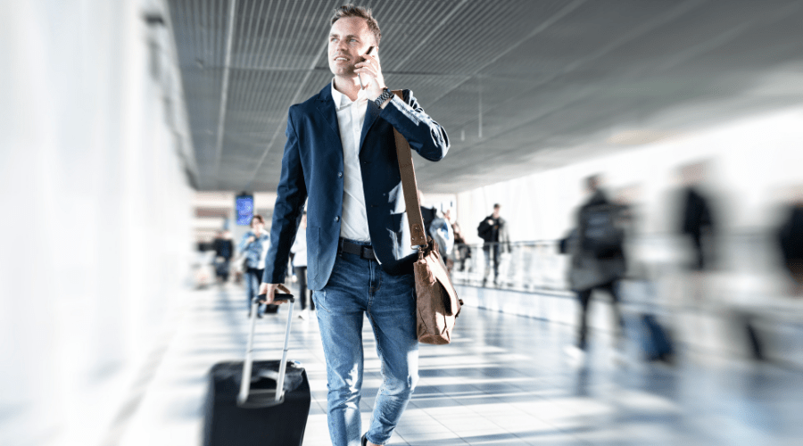 business man talking on cell phone while walking through an airport