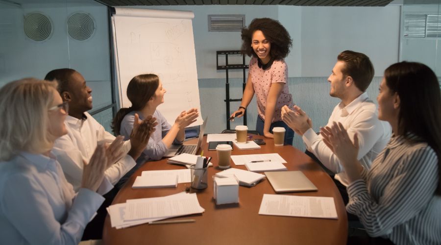 woman giving presentation to coworkers who are clapping