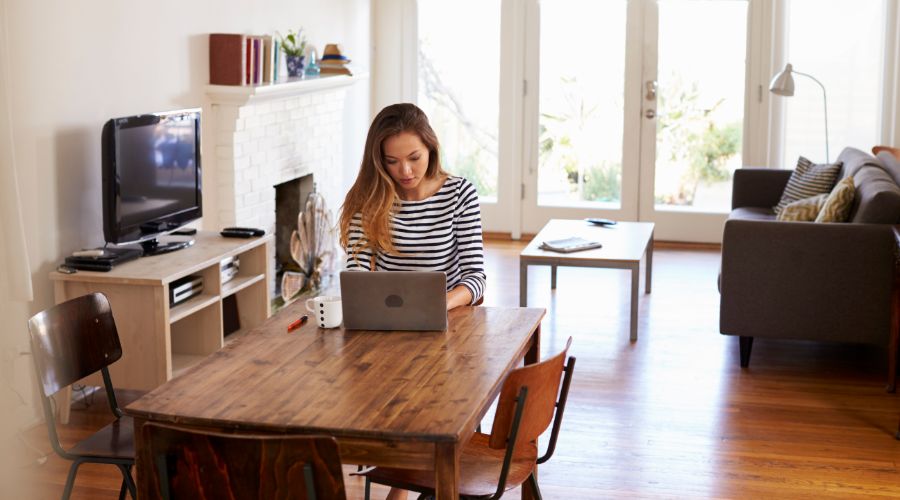 woman working from home by using laptop on her dining room table